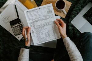 A family reviewing tax forms together at a kitchen table with paperwork, pencils, and a laptop.