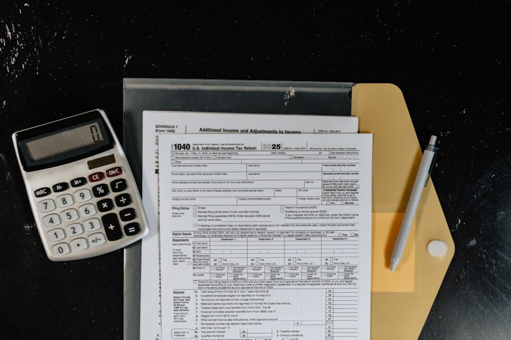 People sorting receipts and a paycheck stub at a kitchen table with a notepad and calculator nearby.