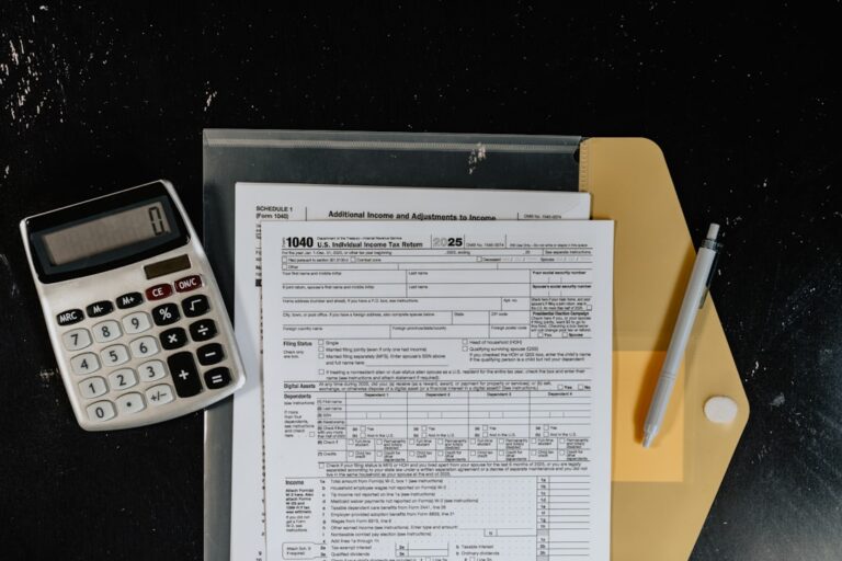 People sorting receipts and a paycheck stub at a kitchen table with a notepad and calculator nearby.
